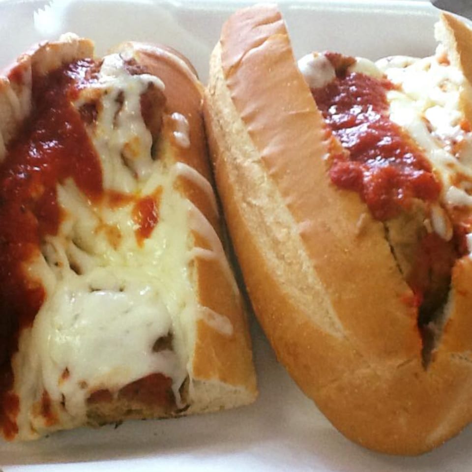 Two meatball subs from Vito's Bistro, topped with melted mozzarella cheese and marinara sauce.