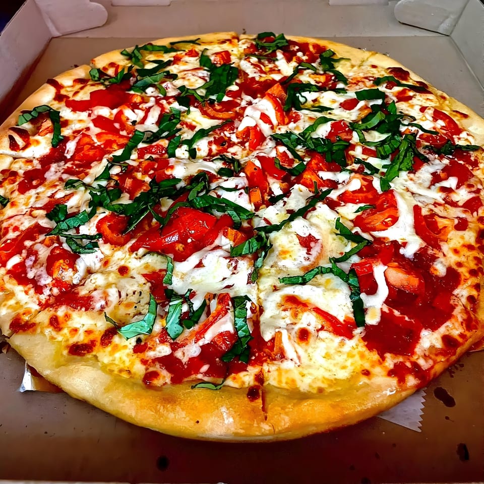 Vito's Bistro Margherita pizza with fresh basil, tomatoes, and mozzarella in a delivery box.