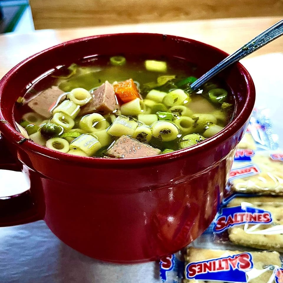 Hearty Italian soup with pasta, vegetables, and meat in a red bowl, served with Saltines.
