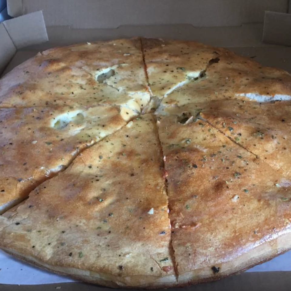 A large, golden-brown calzone, sliced into wedges, sits inside a cardboard pizza box.