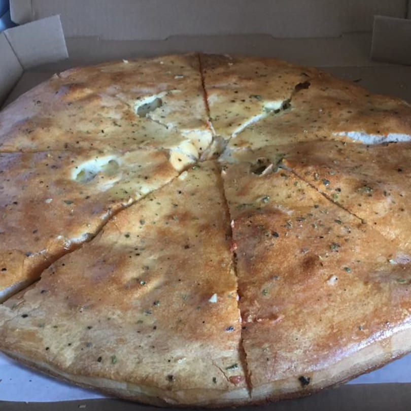 A large, golden-brown calzone, sliced into wedges, sits inside a cardboard pizza box.